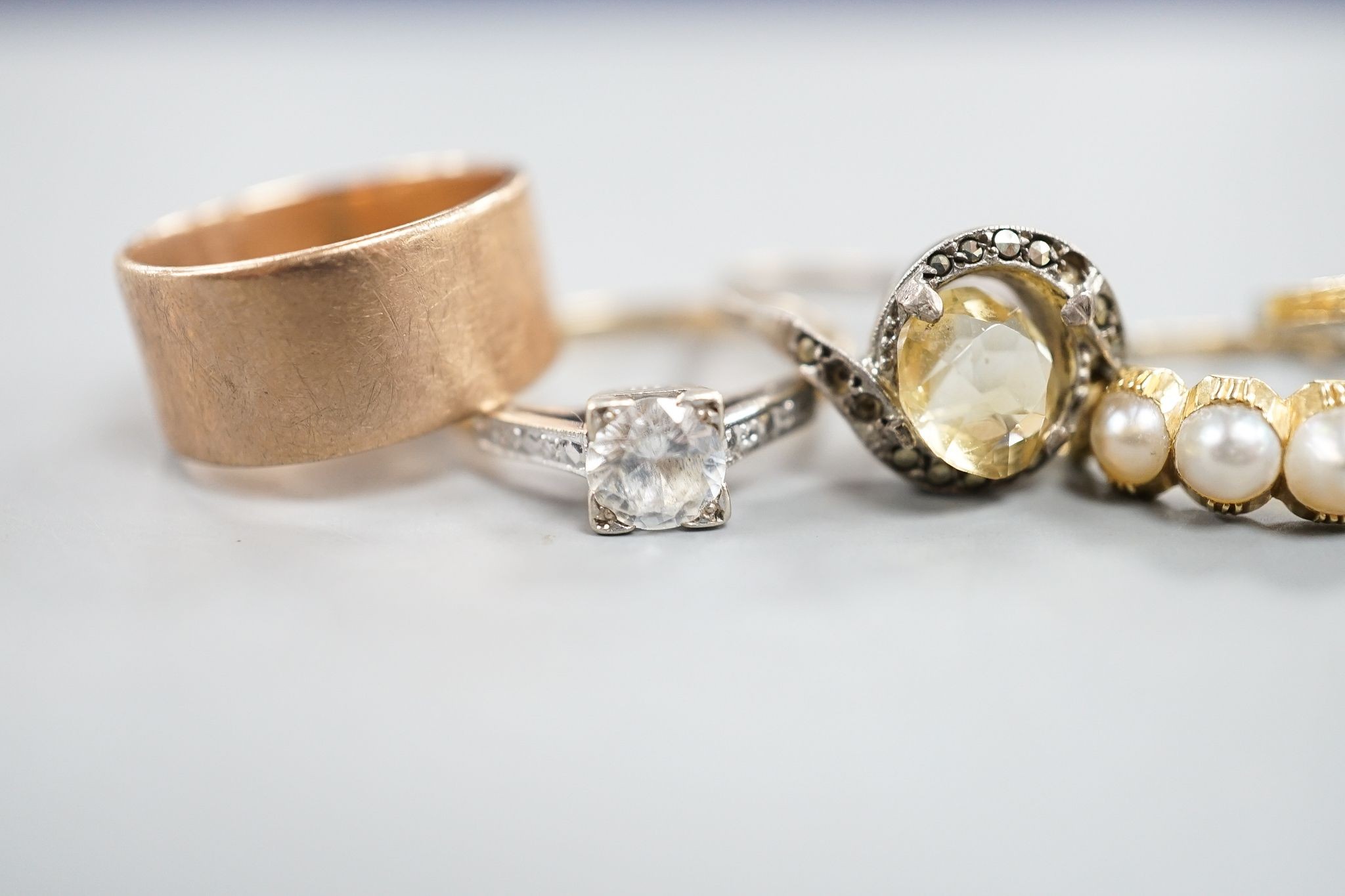 A 9ct gold wedding band, 4.8 grams, a yellow metal and split pearl set half hoop ring, a black onyx and diamond chip set ring, a 9ct and paste ring and one other ring.